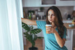 © Dragana Gordic - Contemplative Woman Holding Coffee Cup in Cozy Home Kitchen