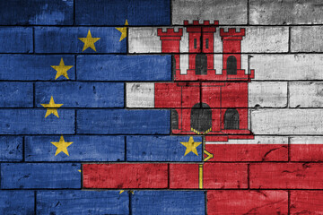 colourful painted big flag of european union and flag of gibraltar on a massive old brick wall background. concept