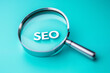 © Denis - Magnifying glass focusing on SEO letters title inscription, company business background. Search engine optimization and digital marketing work efficiency.