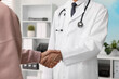 © New Africa - Doctor shaking hands with patient in hospital, closeup