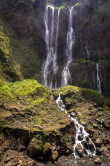 Wall Mural - A stunning and majestic Tumpak Sewu Waterfall cascades gracefully down rugged rocky cliffs, enveloped by lush, vibrant greenery, showcasing the breathtaking beauty of nature, East Java, Indonesia