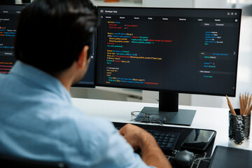 Concentrating in smart IT developer working software development coding on two pc screen, creating virus firmware application program for latest update version on website at modern office. Surmise.
