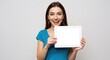 © Deamard - A woman, happy and smiling, with a tablet turned to display its white screen.