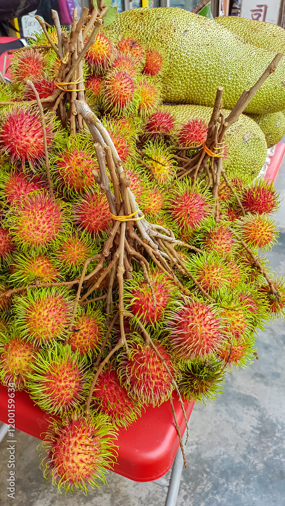 Strane Rambutan Cart Collection of rambutan and jackfruit are displayed on a red surface of ...