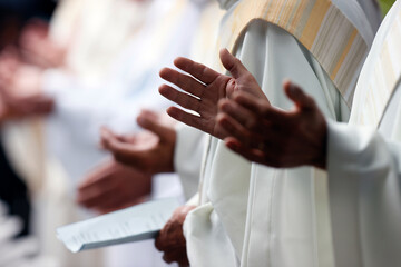 Wall Mural - Catholic mass. Lord's Prayer. Priest praying. Close-up on hands.  La Roche sur Foron..  France.