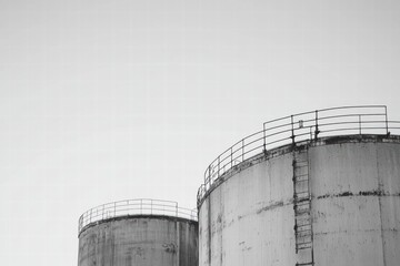 Poster - Large steel oil storage tanks in an industrial area with clear sky during daylight hours. Generative AI
