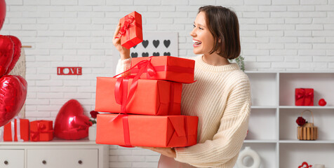 Beautiful young woman with gift boxes in living room. Valentine's Day celebration