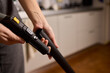 © Евгений Вершинин - Hands actively using a vacuum cleaner in a clean and modern kitchen environment