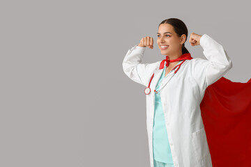 Poster - Beautiful female doctor in superhero costume showing muscles on white background