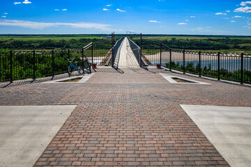 Wall Mural - A brick walkway with a bridge over a river