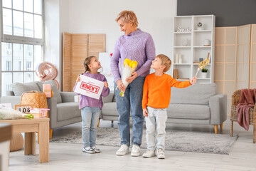 Wall Mural - Little children with gifts and their grandmother at home. International Women's Day