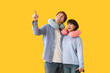 © Pixel-Shot - Couple of young tourists with neck pillows pointing at something on yellow background