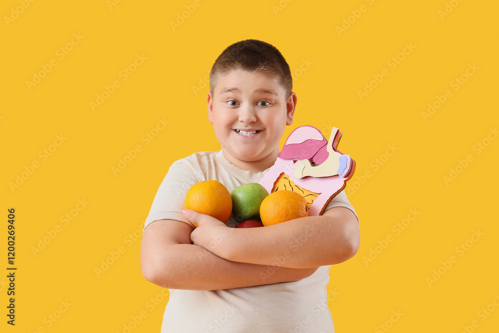 Overweight boy with fruits and paper digestive system on yellow background. Diet concept