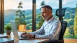 © demzp - Man working on laptop in office with mountain view during sunset hours