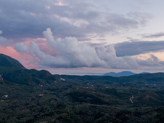 Wall Mural - Serene landscape with rolling hills, lush greenery, and dramatic clouds at sunset.