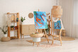 © Pixel-Shot - Interior of artist's workshop with paintings on easels, art supplies and shelving unit