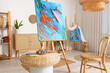 © Pixel-Shot - Paintings on easels and coffee table with art supplies in workshop