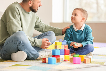 Canvas Print - Happy father and his little son playing with colorful cubes on floor at home