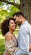 © deFusum - Couple secret whisper: Happy couple embracing under a tree in a sunny park