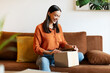 © Home-stock - My online order is here. Happy young woman receiving package, sitting on sofa and opening carboard box at her home interior