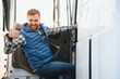 © Serhii - Truck driver climbing into the cab of a semi-truck on bright sunny day