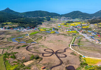 Aerial view of Cheongsan Marine Healing Park with deck trail and marsh against houses of a village at Sinheung-ri of Cheongsando Island, Wando-gun, South Korea