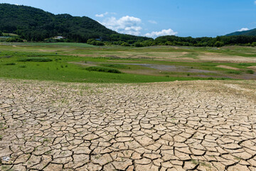 Summer view of land with cracks due to drought against grass on the hill at Soyang River of Inje-gun, South Korea