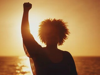 Woman raising fist at sunset: silhouette of empowerment and hope