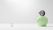 © ArtBackground - Savings money concept design of wooden people with green piggy bank and target dart on white background with copy space 3D render