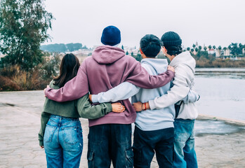 Four young multiracial friends are hugging, enjoying a moment of togetherness and friendship