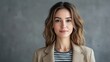 © ifoto - Headshot of a female project manager, approximately 30 years old, wearing a beige jacket and striped shirt against a grey background