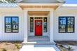 © NusratJahan - Red front door of modern farmhouse with white porch and flower pots