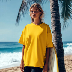 Wall Mural - Women's yellow oversized t-shirt mockup. Beautiful young female model in short sleeve tee, stands by the sea with surfboard at tropical beach with palm trees. Beach, ocean vacation, holiday designs
