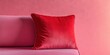 © Ahmad - Red velvet cushion positioned on a soft pink sofa against a smooth pink backdrop creating a harmonious color balance and cozy ambiance.