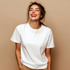 Laughing young woman model with messy hairstyle, dressed in white oversized t-shirt standing near plain background, studio shot. Blank short sleeve tee template. Women crewneck basic tshirt mock up