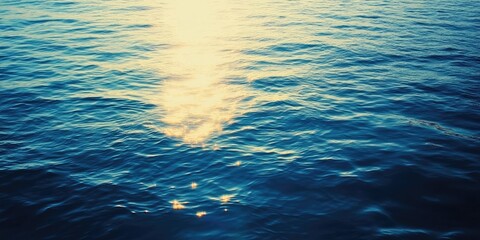 Wall Mural - calm sea at dusk reflecting golden sunlight with gentle waves and deep blue hues in the foreground c