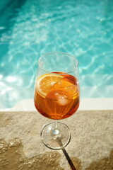 Refreshing drink by the poolside in bright sunlight with citrus garnish creating a relaxing atmosphere