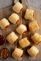 Wall Mural - Homemade Pigs in a Blanket with Ketchup and Mustard on a Wooden Board, top view. Flat lay, overhead, from above.