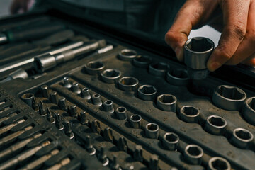 Aufkleber - Hand selecting a metal socket wrench piece from an organized tool tray in a workshop setting, symbolizing precision and automotive repair