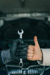 Aufkleber - Close-up of a mechanic's gloved hand holding a wrench and a customer's hand giving a thumbs-up, symbolizing satisfaction and trust in car repair services