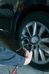 Aufkleber - A mechanic checks tire pressure with a gauge during routine car maintenance in a garage. Focus on the wheel and the instrument ensuring optimal vehicle safety and performance