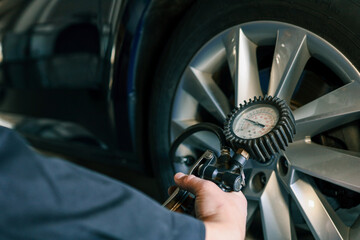 Aufkleber - A mechanic checks tire pressure with a gauge during routine car maintenance in a garage. Focus on the wheel and the instrument ensuring optimal vehicle safety and performance
