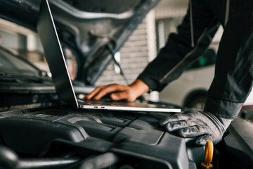 Aufkleber - A mechanic using a laptop on a car engine for diagnostics in a garage. Highlights the use of technology in modern vehicle maintenance and repair