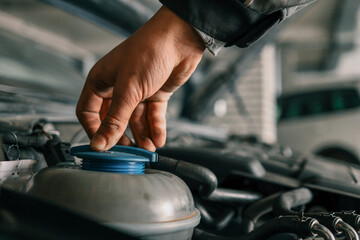 Aufkleber - Mechanic tightening or loosening a blue cap on a vehicle's engine component during maintenance work in an auto repair workshop