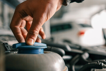 Aufkleber - Mechanic tightening or loosening a blue cap on a vehicle's engine component during maintenance work in an auto repair workshop