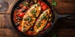 © Gular - Baked tilapia fish enhanced with tomato, pepper, olives, and capers presented in a frying iron pan on a rustic wooden table, showcasing the delightful appeal of baked tilapia fish dishes.