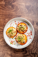 Wall Mural - Deliciously plated mini savory cakes topped with sautéed mushrooms and onions, garnished with fresh herbs and chili flakes, served in a white dish on a wooden table.