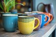© nsit0108 - Vibrant ceramic mugs in various colors arranged on a wooden shelf, creating a cozy kitchen atmosphere