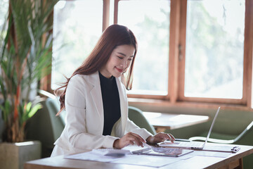 Wall Mural - Professional businesswoman analyzing charts and financial data on laptop, focusing on accounting and budgeting and reviewing documents and reports.