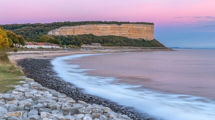 Poster - Coastal cliff and beach at sunset with calm water, soft light, and gentle waves.